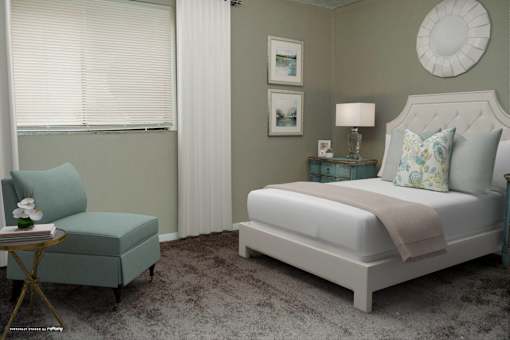 A bedroom with a large bed and a small chair.