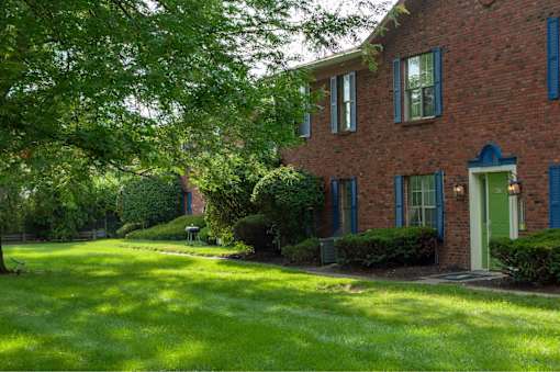 A red brick house with a green door and a green lawn.