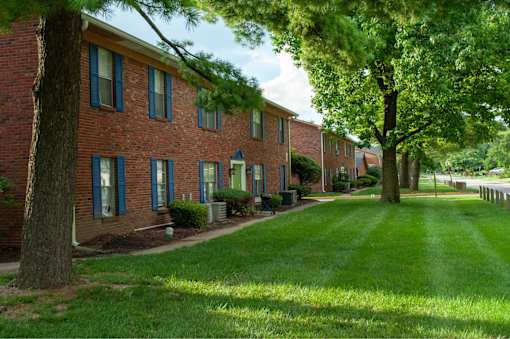 A long brick building with green trees in front.