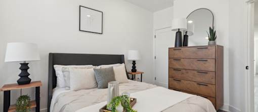 A bedroom with a large bed and a wooden dresser.