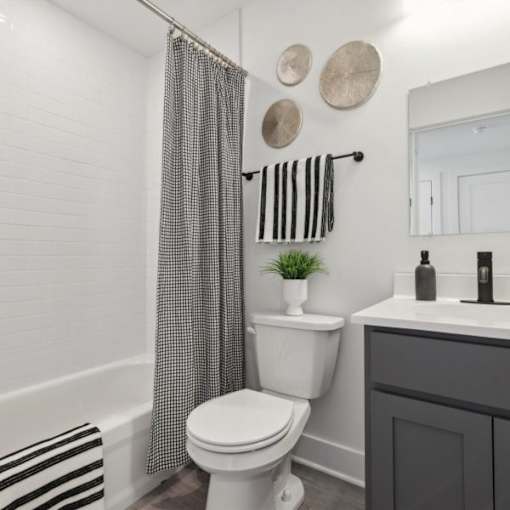 A white toilet sits next to a white bathtub in a bathroom.