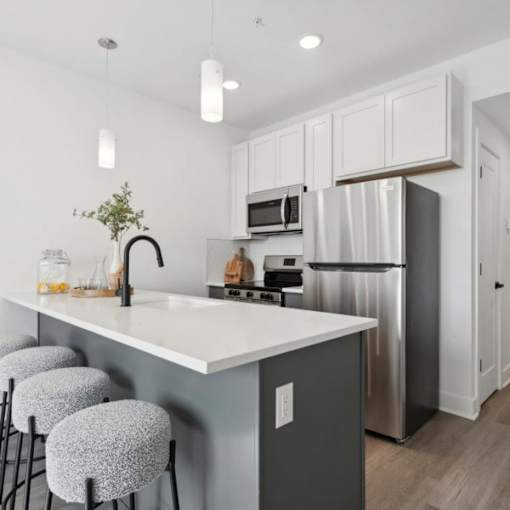 A kitchen with a white countertop and grey bar stools.
