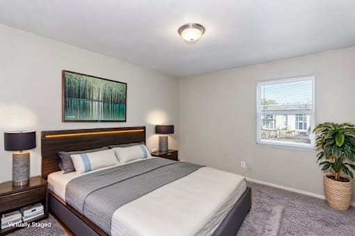 A bedroom with a large bed, two lamps, a painting, and a potted plant.