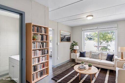 A living room with a white couch, a wooden bookshelf, and a rug.