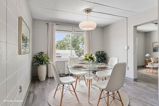 A dining room with a glass table and white chairs.