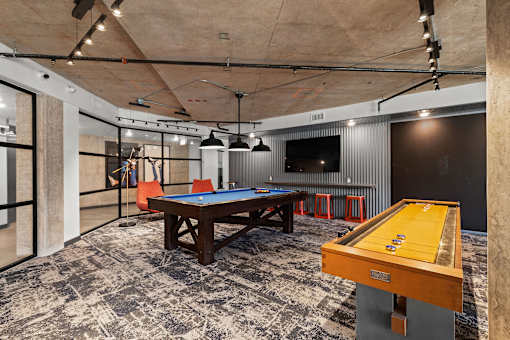 A pool table with a yellow cloth and a wooden table with a brown top.