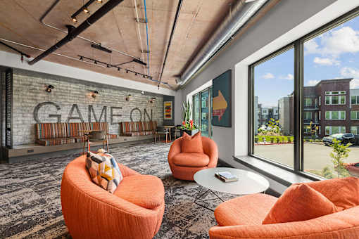A room with orange chairs and a sign that says "GAME ON".