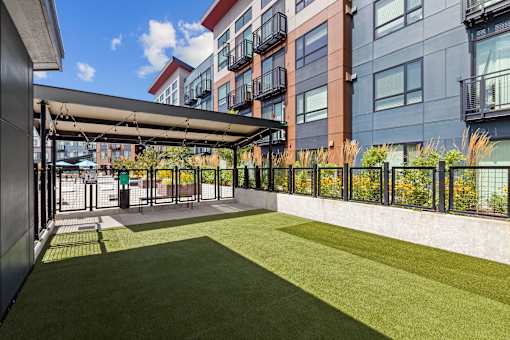 A patio with a metal awning and a green lawn in front of a building.