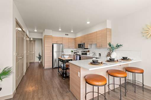 A kitchen with a white counter top and brown bar stools.