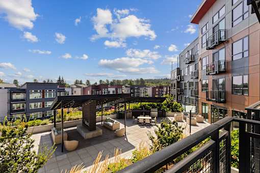 A patio area with a black railing and a black pergola.