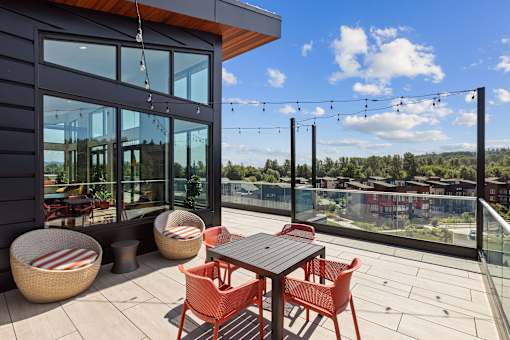 A patio with a table and chairs overlooking a cityscape.