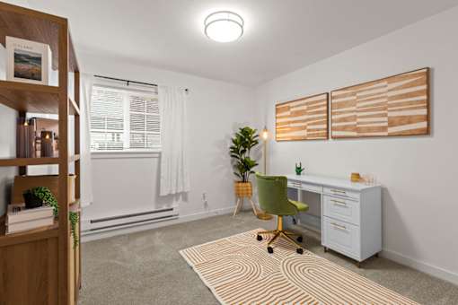 A room with a desk, chair, and two artworks on the wall.