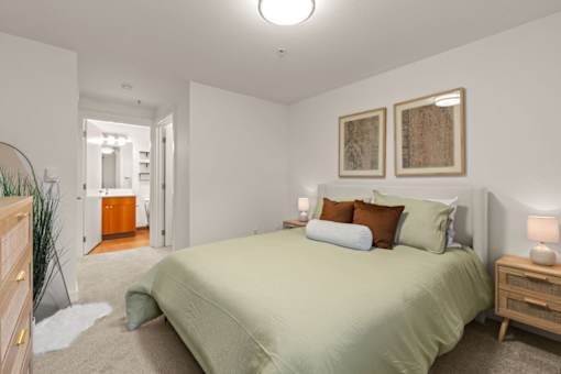A bedroom with a bed, nightstands, and two framed pictures on the wall.