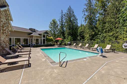 A swimming pool surrounded by lounge chairs and trees.