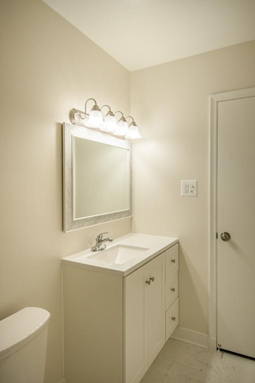 A white bathroom with a sink, mirror, and toilet.