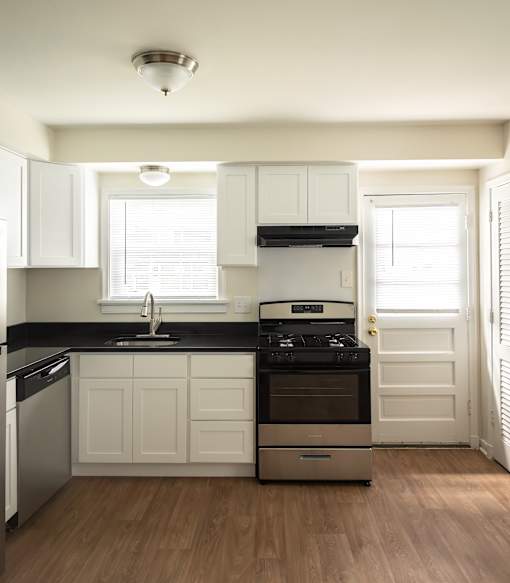 A kitchen with white cabinets and black countertops.