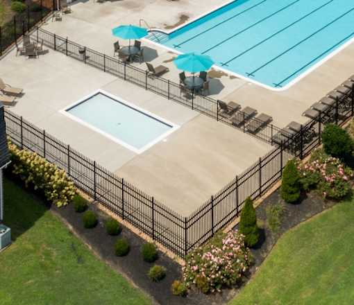 A black fence surrounds a small pool with a blue umbrella.