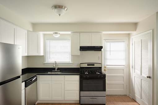 A kitchen with white cabinets and black countertops.