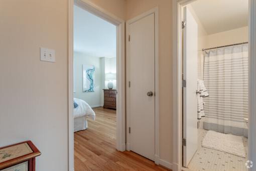 A white door is open to a room with a bed and a painting.