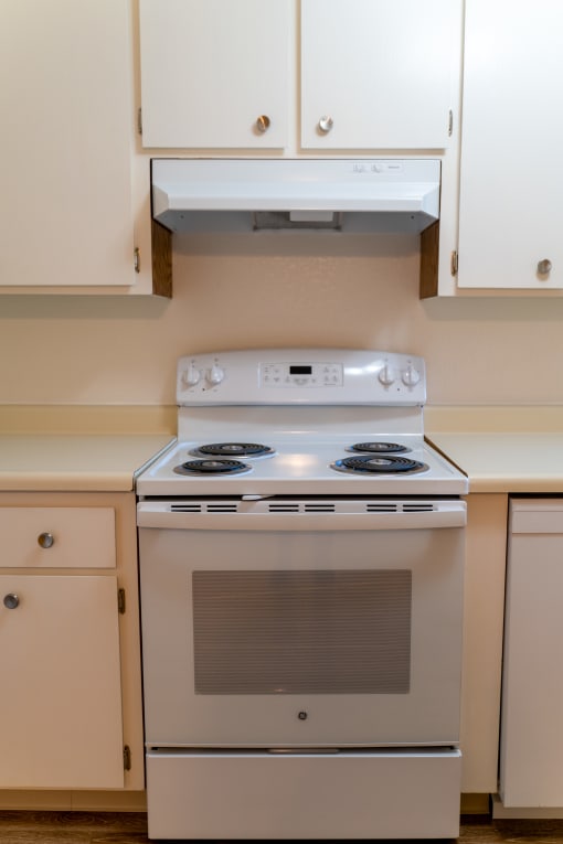 a white stove top oven in a kitchen with white cabinets at Cowell Terrace Apartments, Concord California