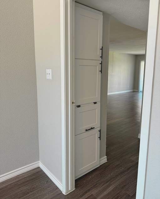 an open white door leading into a hallway with a wood floor