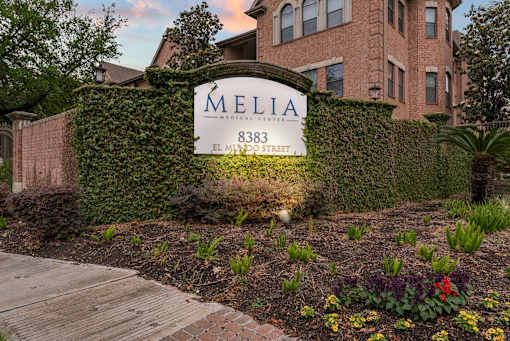 A sign for Melia Medical Center is displayed in front of a brick building.