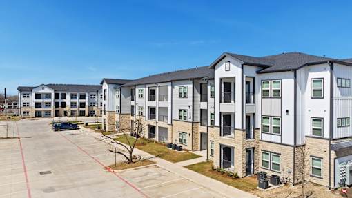 A parking lot is in front of a building with multiple stories.