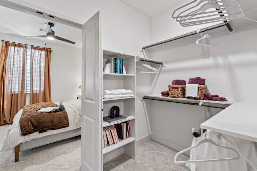 A bedroom with a bed, a desk, and a fan.