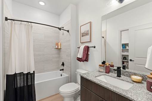 A bathroom with a white toilet, a white bathtub, a sink, and a mirror.