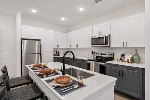 A kitchen with a white counter top and black chairs.