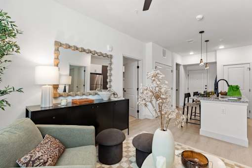 A living room with a grey couch and a mirror above a dresser.