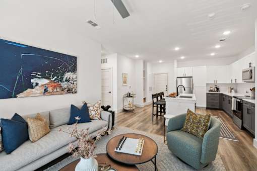 A modern living room with a grey sofa and a painting on the wall.