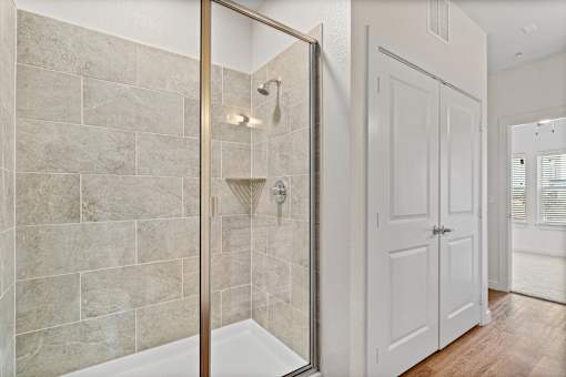 A bathroom with a walk-in shower and a white door.