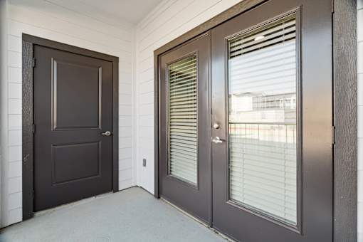 A brown door is on the left and a brown door with blinds is on the right.