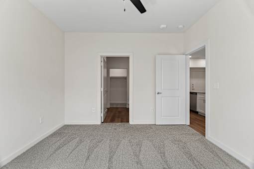A room with a carpeted floor and a ceiling fan.