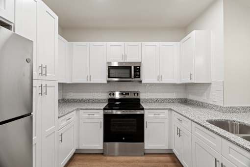 A kitchen with white cabinets and a black stove top oven.