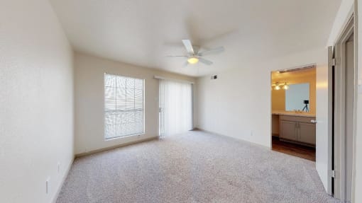an empty living room with a ceiling fan and a window
