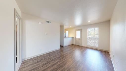 the living room and dining room of an empty house with wood flooring