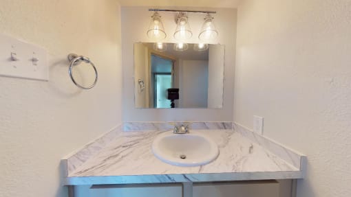 Bathroom sink with white countertop and mirror with lights