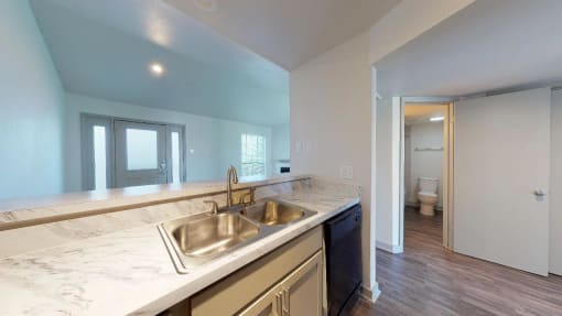 Kitchen sink surrounded by white countertops and looking into living room