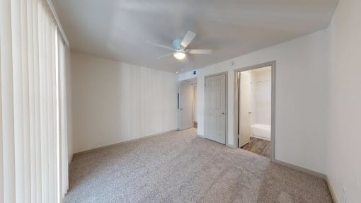 a bedroom with carpet and a ceiling fan and a door to a bathroom