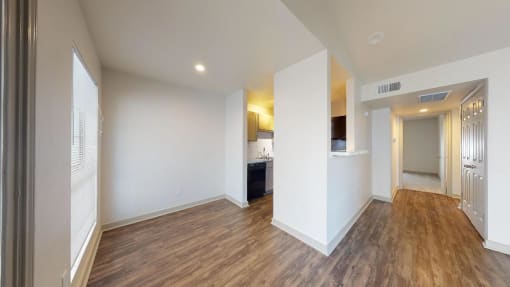 a living room and kitchen with a wood floor and white walls