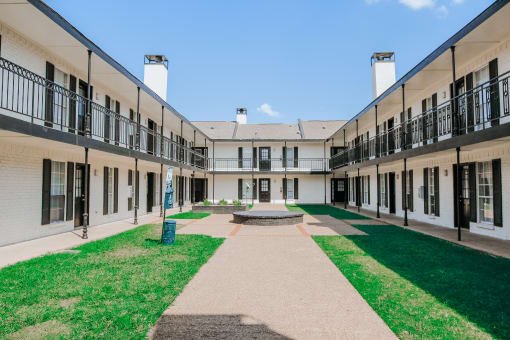 the courtyard of a building with grass and a fountain