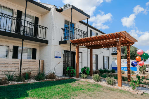 the exterior of a building with a pergola and grass