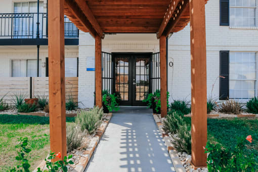 the front entrance of a building with a walkway and wooden beams