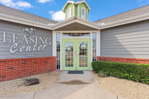 A building with a green door and a sign that says Leasing Center.