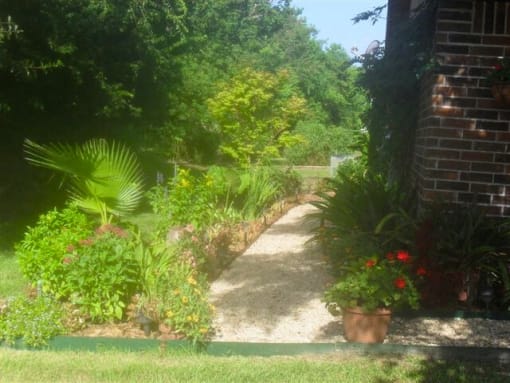 a pathway in a garden next to a brick building