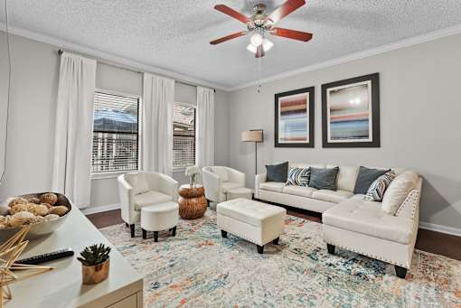 A living room with a white sofa, two chairs, and a rug.