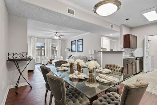 A modern dining room with a glass table and grey chairs.