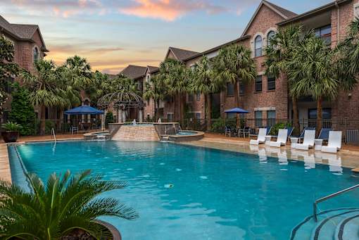 A swimming pool surrounded by palm trees and lounge chairs.